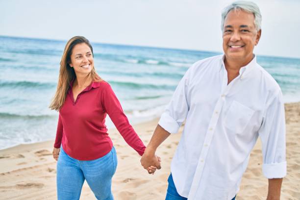 istock Middle age hispanic couple smiling happy walking at the beach. 1364436509