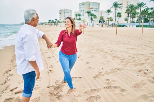 一緒に幸せで陽気なビーチで踊る愛の中年のカップル - senior adult retirement mature adult couple ストックフォトと画像