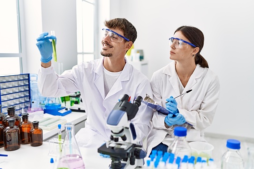 Man and woman partners wearing scientist uniform working at laboratory