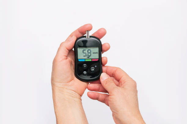 Close-up of the hands of a woman using a glucose meter to measure blood sugar level. Health care Close-up of the hands of a woman using a glucose meter to measure blood sugar isolated on a white background. Checking blood sugar level by glucometer for diabetes testing. Health care. Top view hyperglycemia stock pictures, royalty-free photos & images