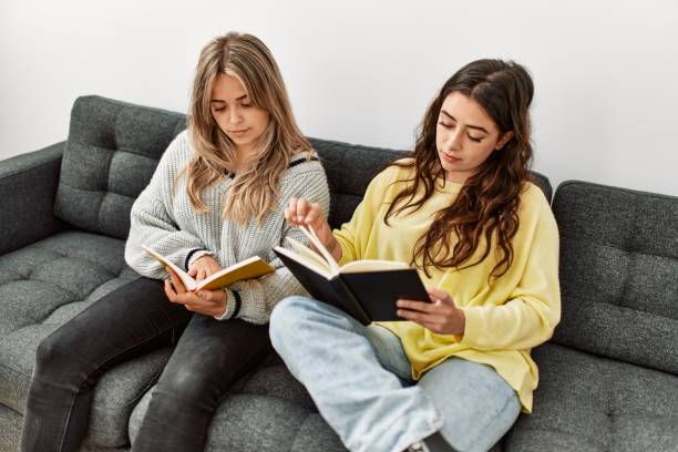 istock Young couple reading book sitting on the sofa at home. 1364438834