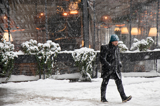 Belgrade, Serbia - January 11, 2022: One man walking  on a snowy winter day in the city in front of a restaurant