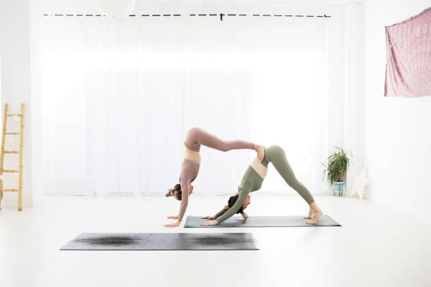 istock A yoga teacher adjusts her student's posture. They are both in downward facing dog pose. 1364441055