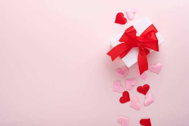 istock White gift boxes with red ribbon and small red decorative hearts on pink background. Top view with copy space. Valentines day or Wedding romantic concept. Festive composition. Mock up. 1364442544