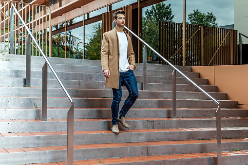 elegant and modern man walking down stairs with positive attitude