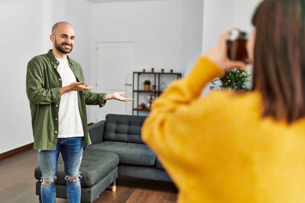 istock Young hispanic woman make photo using camera to man at home. 1364448805