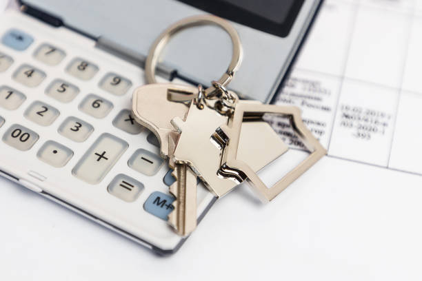 Close-up keys with a metal keychain house are on the calculator. Mortgage and loan termination Close-up keys with a metal keychain house are on the calculator. Mortgage and loan termination. borrowing stock pictures, royalty-free photos & images