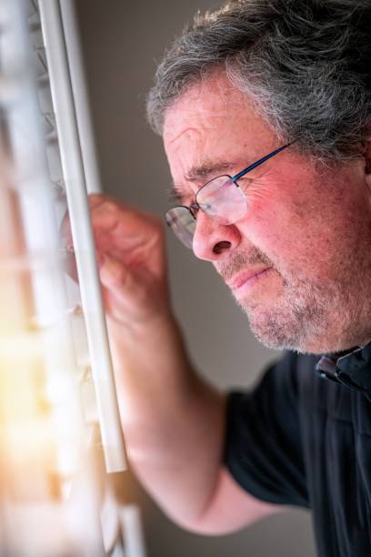 istock Serious, worried, stressed mature man looking through a window 1364450562
