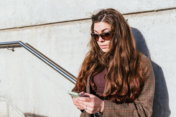 istock Woman leaning on wall and using smartphone 1364451862
