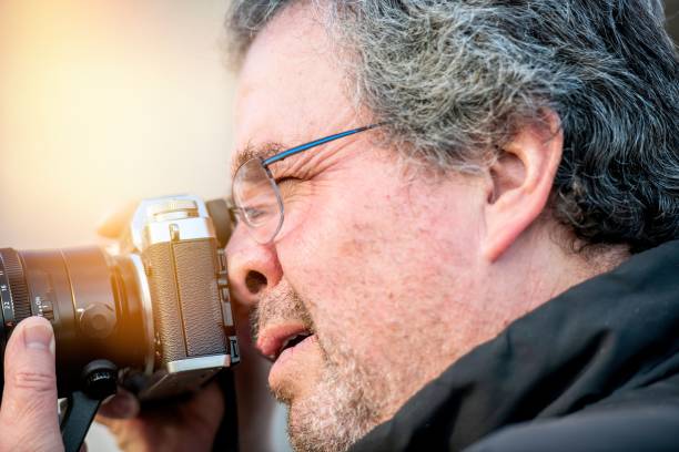 istock Mature man shooting a picture with his camera 1364452147