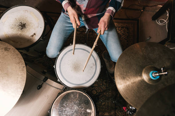 Man playing music on drum set in studio Top view of crop anonymous male musician in casual clothes playing acoustic drum kit during live performance solo performance stock pictures, royalty-free photos & images