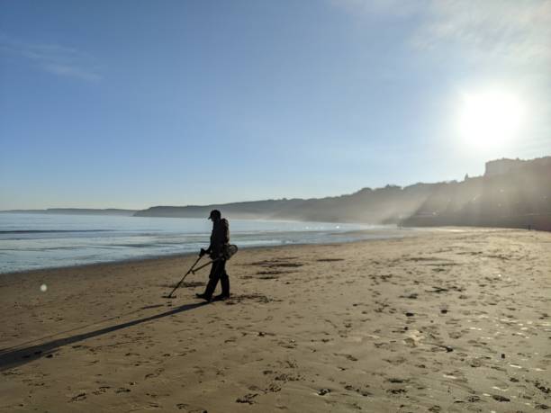 Silhouette of a hobbyist metal detectorist on the beach. Unidentifiable person searching for metal Scarborough South Bay, UK.  December 17 2021. hobbyist stock pictures, royalty-free photos & images