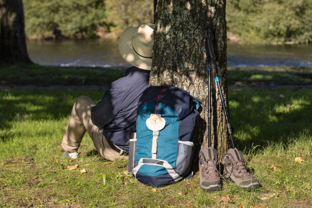 Scene of a Backpack leaning against a tree, boots and accessories and a pilgrim resting on his way to Santiago de Compostela stock photo
