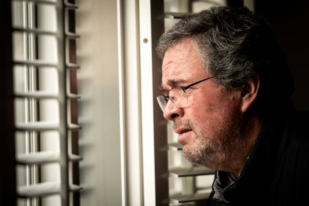 istock Serious, worried, stressed mature man looking through a window 1364457099