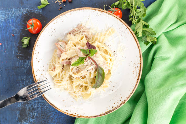 istock Tagliatelle pasta with Carbonara Sauce and Bacon on white plate on blue background 1364457242
