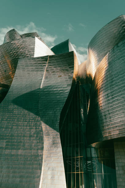 Guggenheim Museum with sunshine on titanium shapes facade in Bilbao city Bilbao, Spain - April 22, 2021: Guggenheim Museum with sunshine on titanium shapes facade in Bilbao city. Modern building architecture designed by Frank Gehry frank gehry building stock pictures, royalty-free photos & images