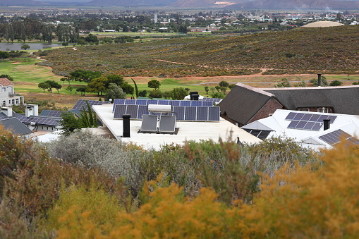 A photograph of houses in Worcester, South Africa with solar panels installed on their roofs.