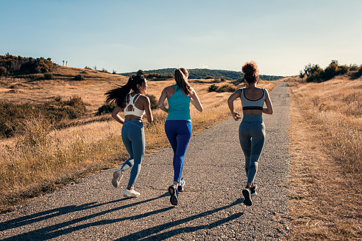 Group of female friends running outdoors.