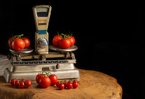 Tomatoes, beautiful tomatoes placed on an old weighing scale, over rustic wood, selective focus.