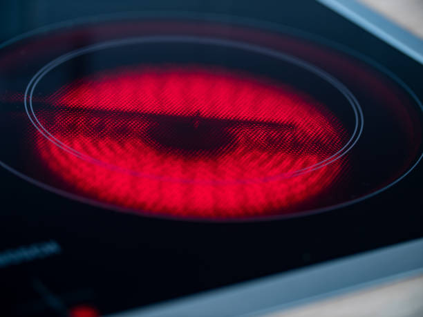 Close-up of kitchen stove with ceramic hob turned on and glowing red.