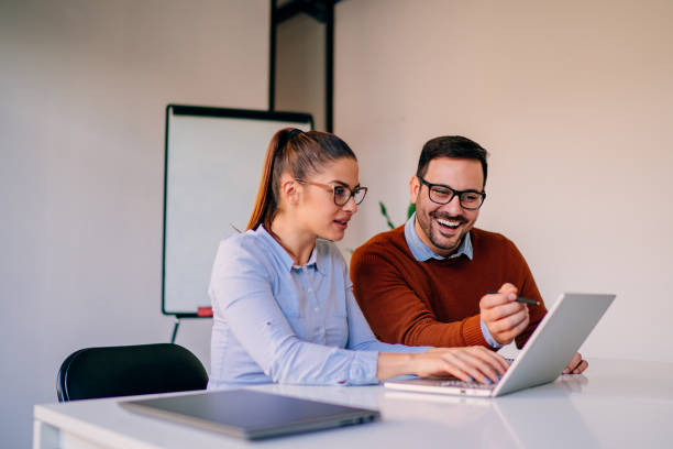 istock Happy businesspeople working together in the office while using laptop 1364467496
