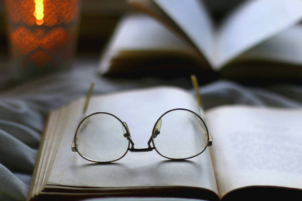 istock Open Books, Reading Glasses and Lit Candle 1364467636