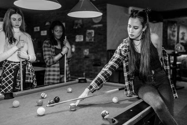Three multi racial female friends playing pool in an entertainment club