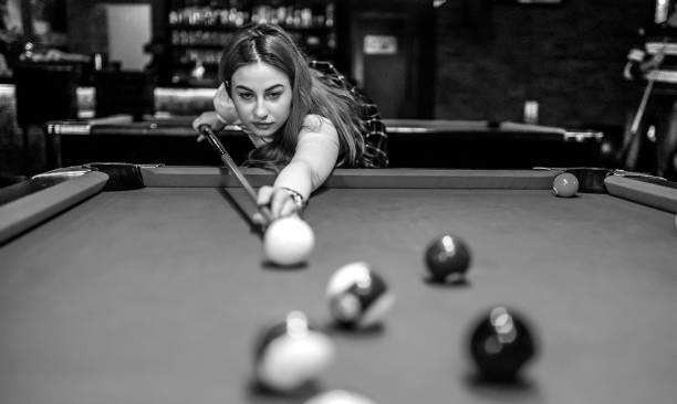 Young caucasian woman aiming and playing pool in the bar