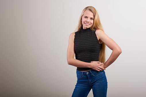 Studio portrait of a attractive young woman posing against a white background in denim jeans and a black tank top