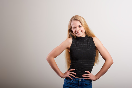 Studio portrait of a attractive young woman posing against a white background in denim jeans and a black tank top
