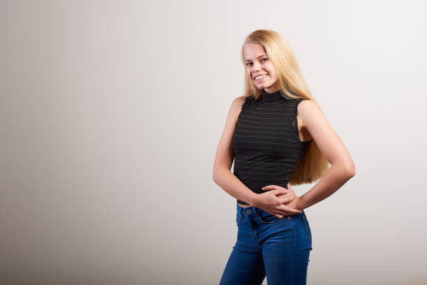 Portrait of a smiling young woman with long blond hair in front of a solid white background stock photo