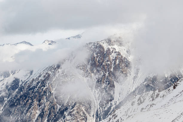 istock Snowy rocky mountains merging with the clouds 1364474568