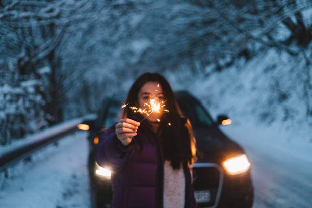 istock Woman lighting sparkles during winter while on a road trip in the mountains. 1364474704