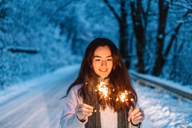 istock Woman lighting sparkles during winter while on a road trip in the mountains. 1364474711