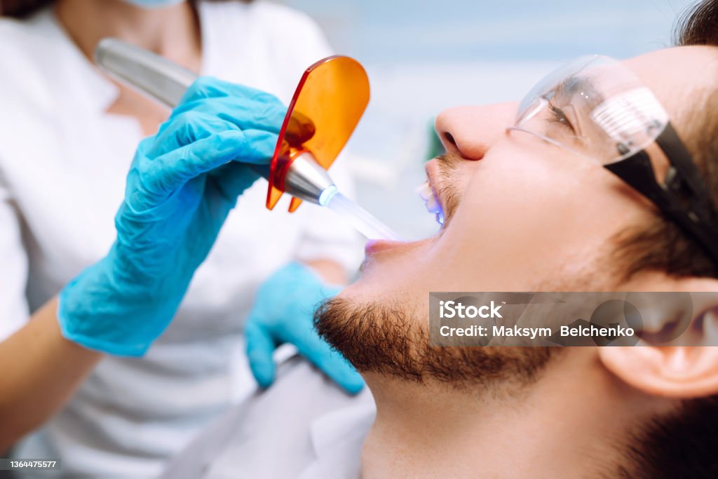 Junger Mann am Zahnarztstuhl während eines zahnärztlichen Eingriffs. Überblick über die Kariesprävention. - Lizenzfrei 20-24 Jahre Stock-Foto