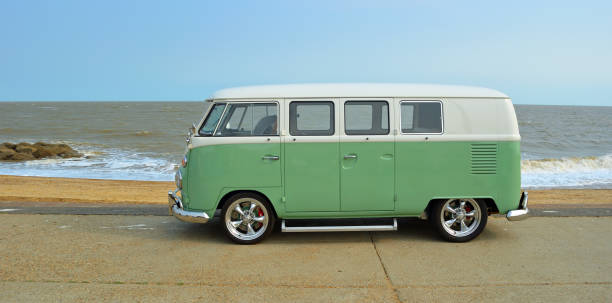 klasyczny zielono-biały vw camper van zaparkowany na nadmorskiej promenadzie. plaża i morze w tle - volkswagen zdjęcia i obrazy z banku zdjęć