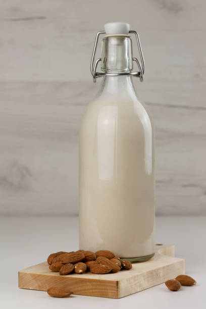 istock Dairy free almond milk in a bottle and nuts on light background 1364481104