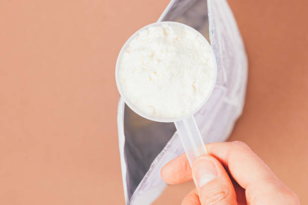 istock Hand holding measuring spoon with portion of protein powder 1364482591