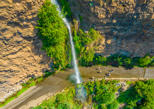 Aerial drone view of Angels waterfall (Cascata dos Anjos) in Madeira island. The waterfall cascades over the rockface onto the regional roadway, and spills into the sea below