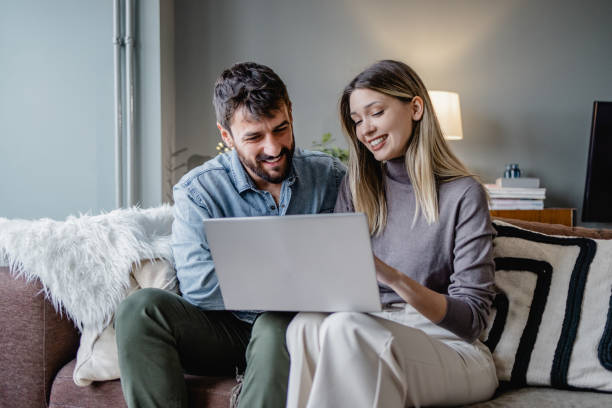 Young couple using laptop at home stock photo