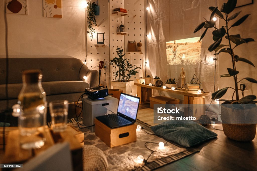 Living room with projector screen and cushions Empty living room with projector screen set up with couch and cushions and lights hanging on wall and floor Domestic Room Stock Photo