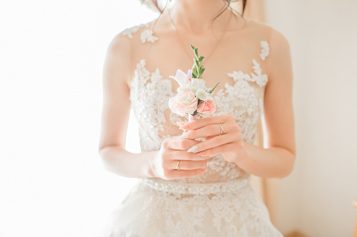 Bright close-up portrait of a bride in a white wedding dress with a flower in her hands. Wedding day and preparation for the wedding ceremony