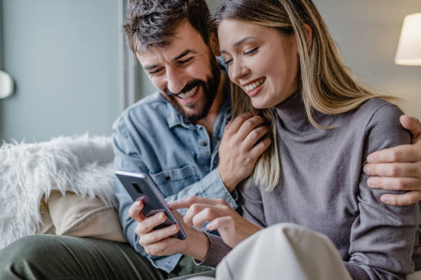 istock Young couple embracing at home and using mobile phone 1364484941