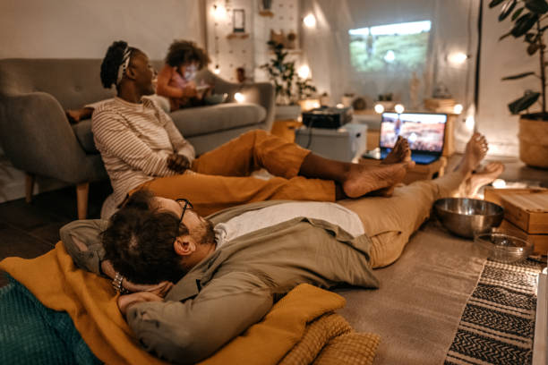 istock Family sitting together watching movie on projector screen 1364485839