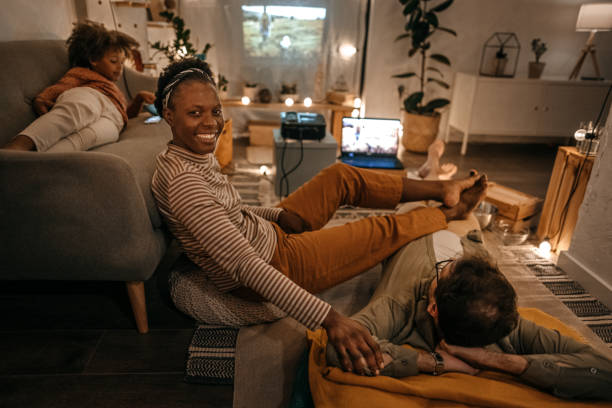 uśmiechnięta kobieta oglądająca film na projektorze z rodziną - projection equipment home interior house living room zdjęcia i obrazy z banku zdjęć