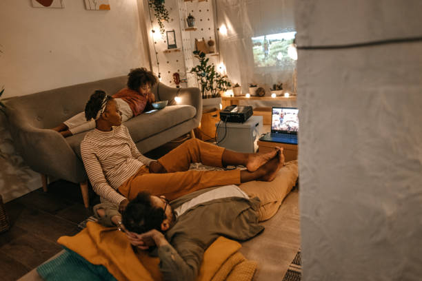 istock Family sitting together watching movie on projector screen 1364485887