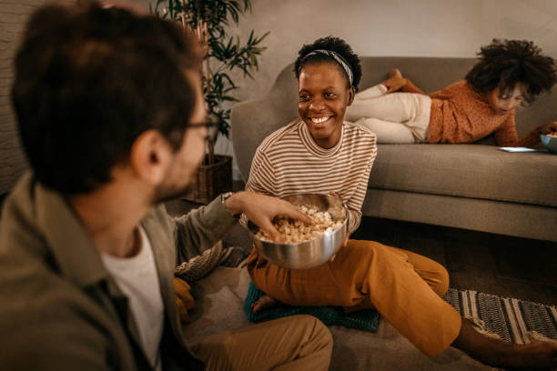 istock Young woman offering popcorn snacks to husband at home 1364485920
