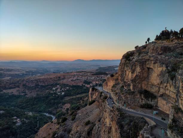 Rocky hill crossed by a road at sunset in Constantine, Algeria Panoramic view of a rocky hill crossed by a road, houses scattered below and mountains on the horizon. Constantine, Algeria algeria stock pictures, royalty-free photos & images