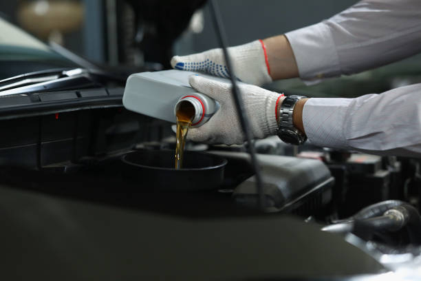 istock Worker refueling and pouring new oil into engine motor of automobile 1364501593