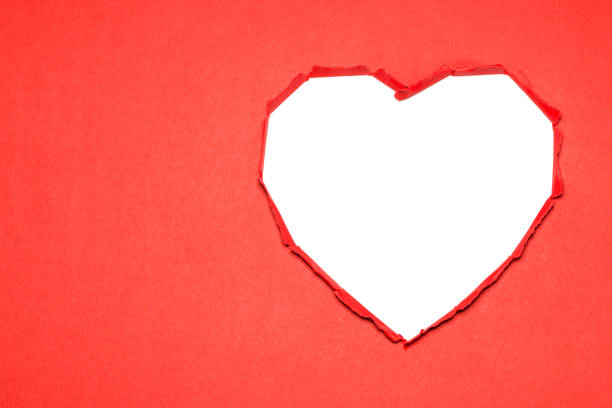 Heart-shaped white hole torn through the red paper. Valentines Day idea.
